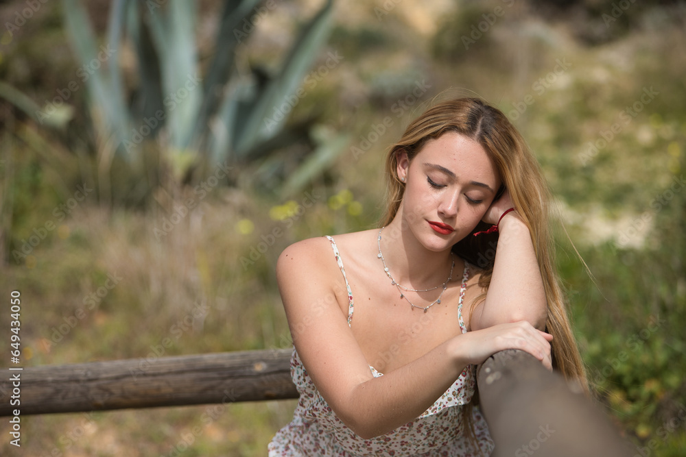 Portrait of young woman, blonde and beautiful, with a suit of flowers, with closed eyes leaning on a railing, sad and melancholic. Spring concept, flowers, sadness, melancholy. Portrait of young woman, blonde and beautiful, with a suit of flowers, with closed eyes leaning on a railing, sad and melancholic. Spring concept, flowers, sadness, melancholy.