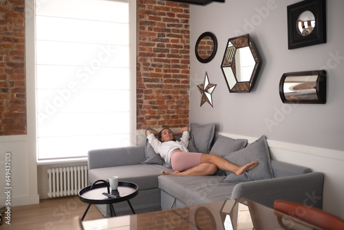 young beautiful woman lies on the sofa in the living room in the apartment