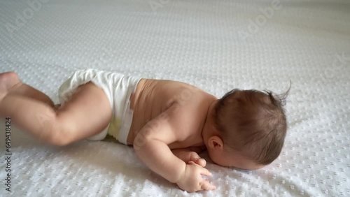 The infant turns over on its tummy for the first time. Development of a child at three months
