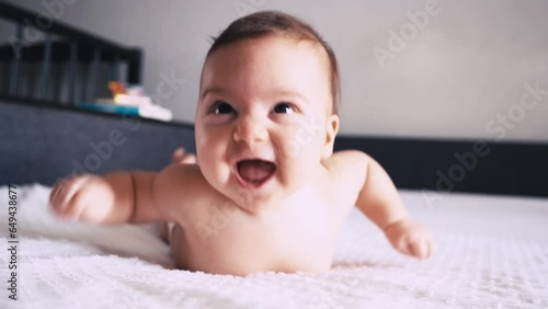 A beautiful cute infant is lying on his tummy and smiling. Life and development of a newborn child.