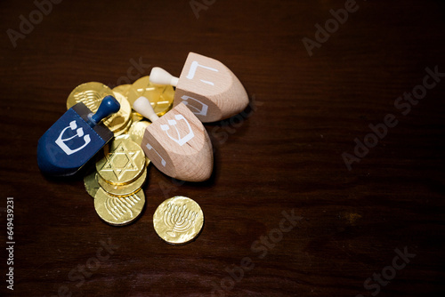 фотографія Top view of three wooden dreidels with gelt and copy space on wooden table