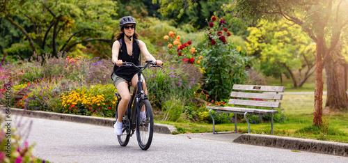 Fit Caucasian Woman riding an Electric Bicycle on a trail in Stanley Park, Downtown Vancouver, British Columbia, Canada