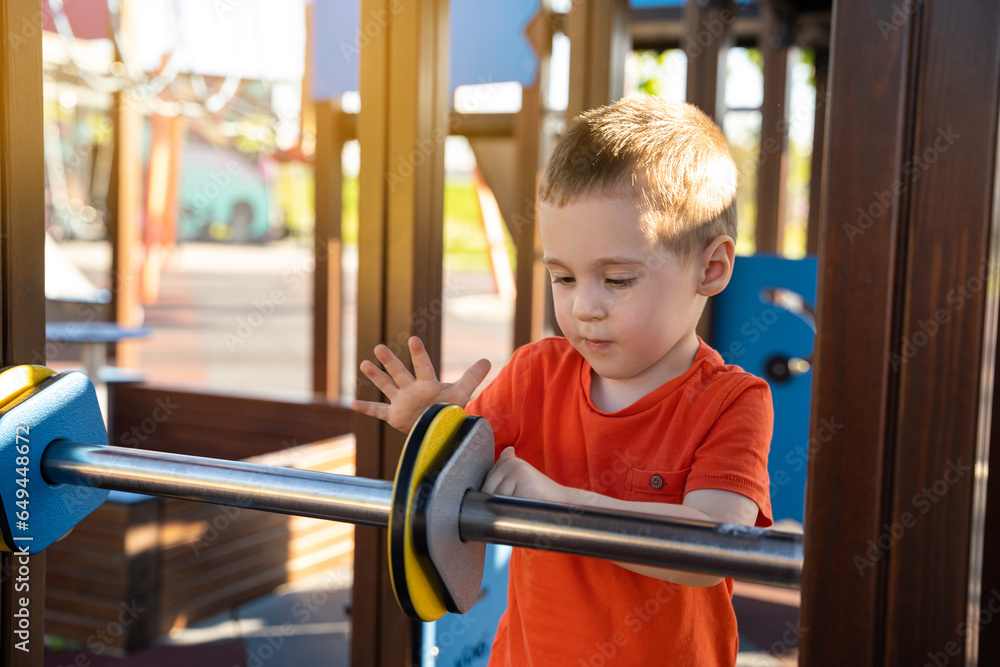 Cute toddler boy two or three years old is playing on the playground with colorful rings on a sunny summer day. Children's games. Close-up. Selective focus Cute toddler boy two or three years old is playing on the playground with colorful rings on a sunny summer day. Children's games. Close-up. Selective focus