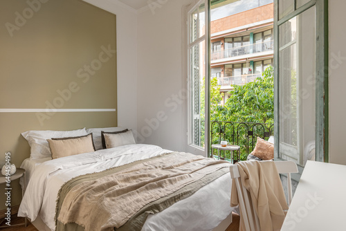Chic double bed against the backdrop of an open window overlooking the sunny summer weather. Honeymoon hotel room concept. Copyspace