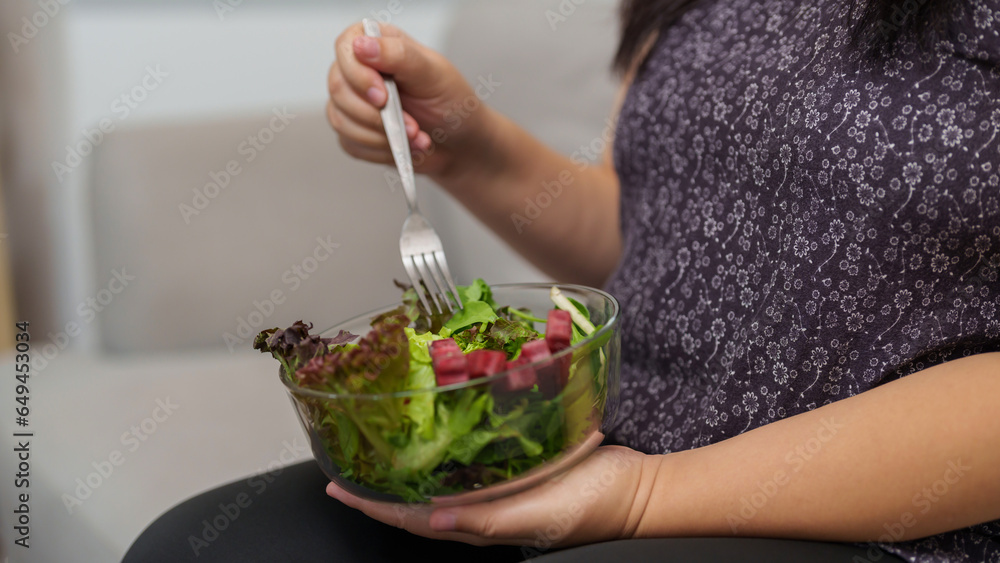 Overweight woman enjoy eating a bowl of vegetable salad at her home Overweight woman enjoy eating a bowl of vegetable salad at her home