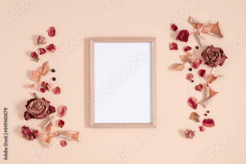 Autumn composition of dry flowers. Blank photo frame, fall dried flowers, leaves and berries on beige background. Flat lay, top view, copy space.