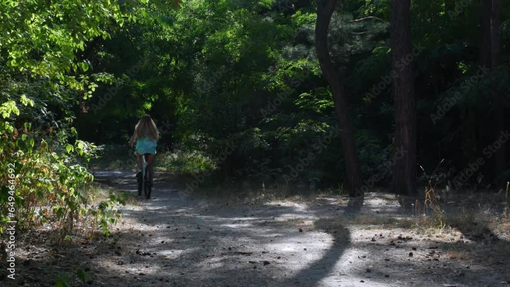 A girl wearing a green blouse is riding a bicycle through the forest. An exciting bike ride through the pine park. High quality 4K video A girl wearing a green blouse is riding a bicycle through the forest. An exciting bike ride through the pine park. High quality 4K video