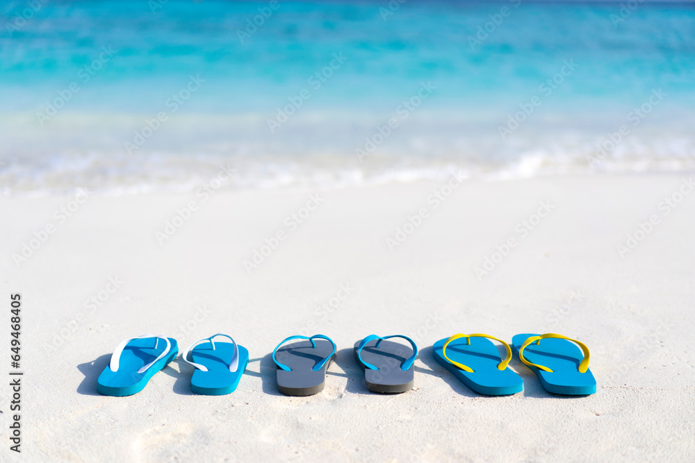 Obraz premium Three pairs of flip flops on the beach on the background of ocean in the Maldives. Family vacation