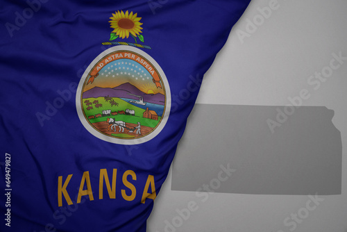 big waving national colorful flag and map of kansas state on the gray background. photo