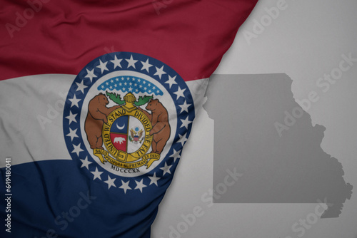 big waving national colorful flag and map of missouri state on the gray background. photo