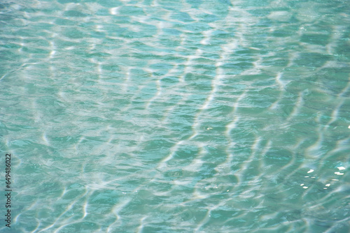 Defocus blurred transparent blue colored clear calm water surface texture with splashes reflection. Trendy abstract nature background. Water waves in sunlight with copy space. Blue watercolor shine