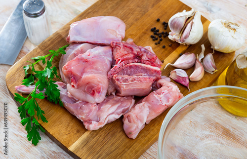 Delicious cutting rabbit meat with spices, knife and herbs on kitchen board