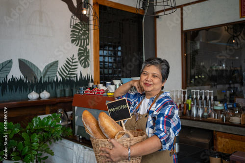 Asian senior  elderly  retired  woman. standing with a bread basket in her coffee shop. Small business  Business owner. 