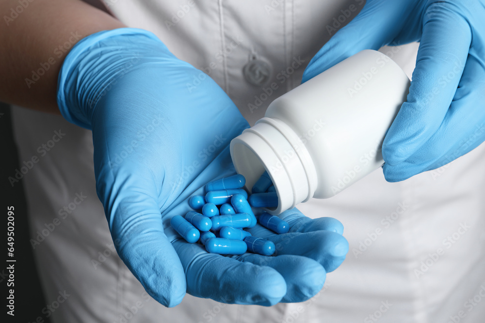 Obraz premium Doctor pouring pills from bottle onto hand, closeup view