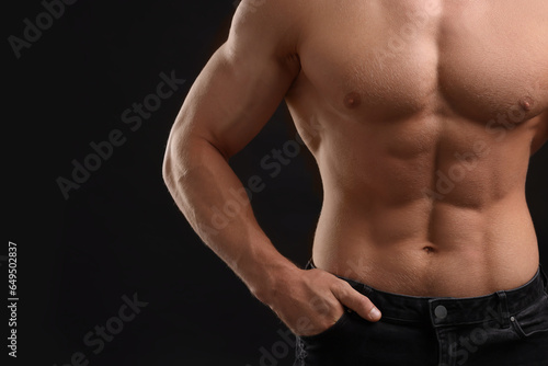 Muscular man showing abs on black background, closeup and space for text. Sexy body