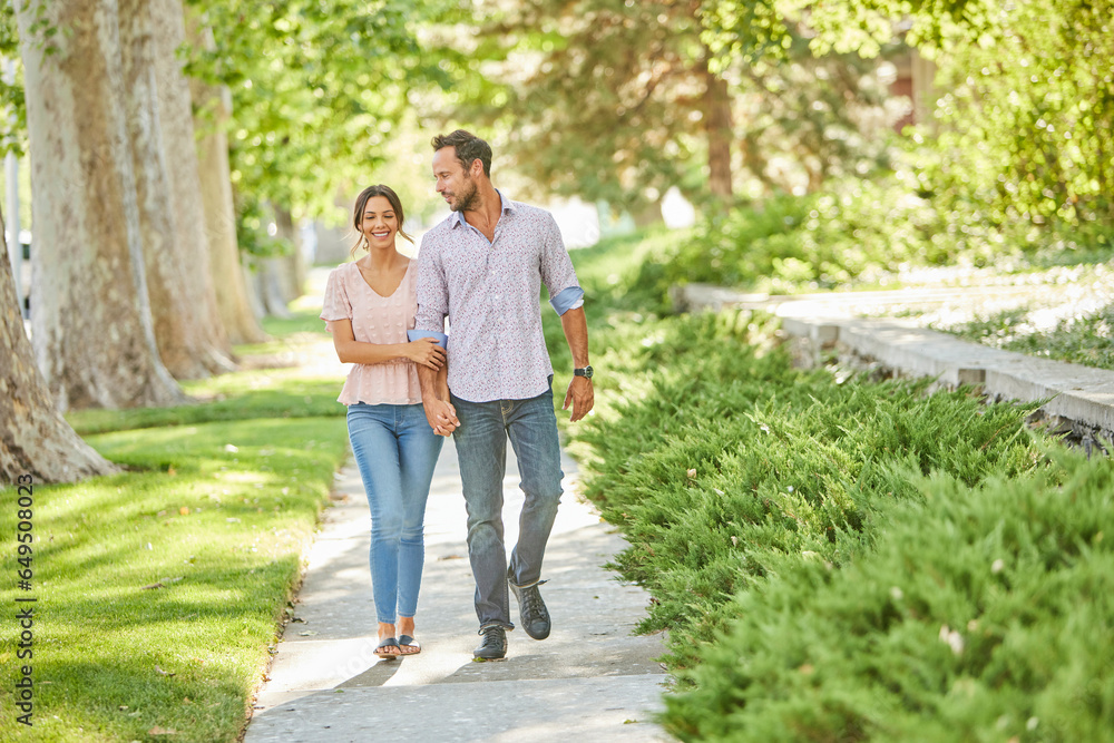 Smiling couple holding hands, walking on treelined sidewalk Smiling couple holding hands, walking on treelined sidewalk