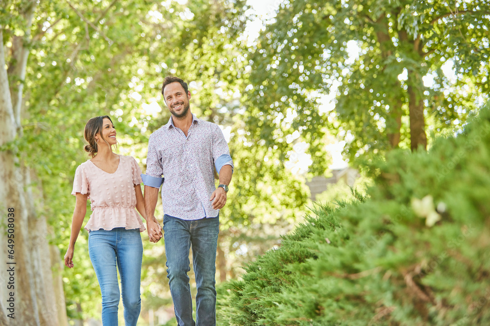 Smiling couple holding hands, walking on treelined sidewalk Smiling couple holding hands, walking on treelined sidewalk