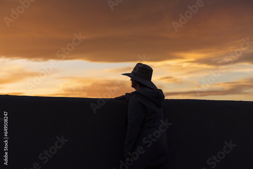 Silhouette of man in hat looking at sunset photo