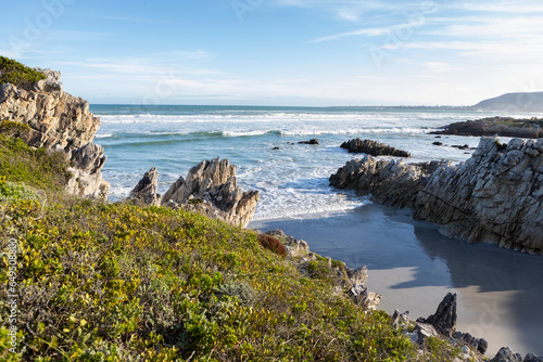 South Africa, Hermanus, Rocky coastline with Atlantic Ocean in Voelklip Beach on sunny day photo