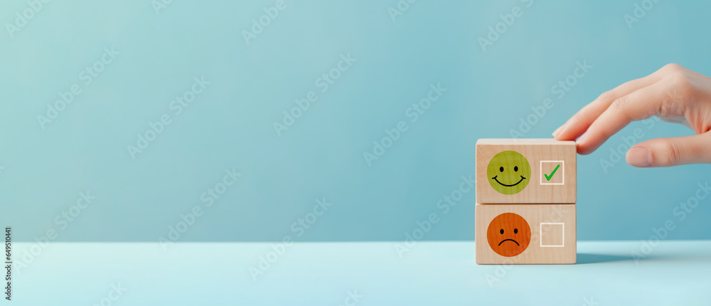 Woman hand choose wood cube with smile and sad icon, World mental health day or feedback rating concept, Positive customer review, Wood cube stacking with emotion face icon on blue background - obrazy, fototapety, plakaty 