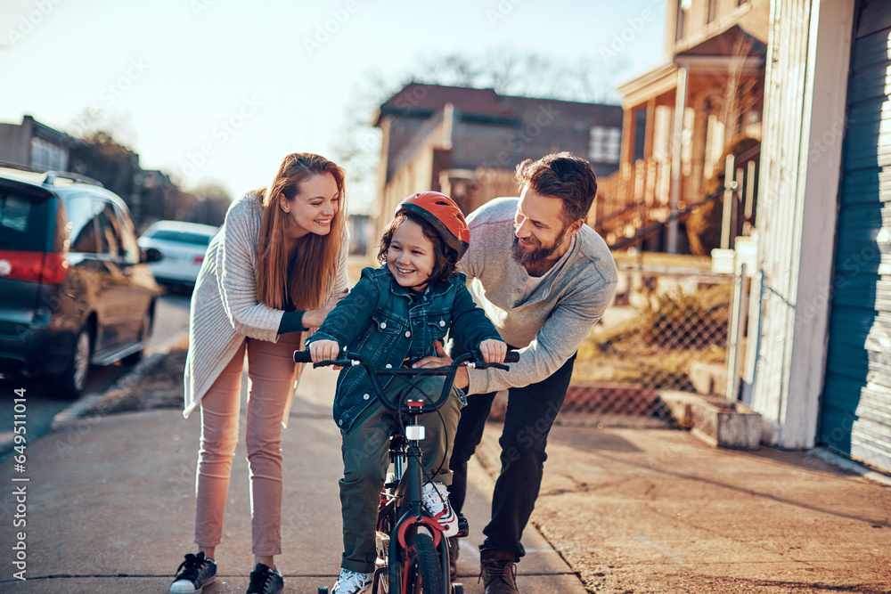 Young Caucasian family teaching their son to ride a bike in the suburbs