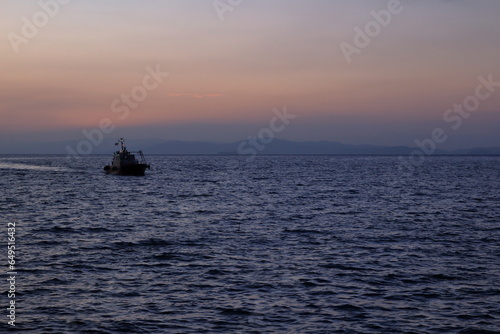 朝焼けの中を港に戻る船 © So Takinoiri