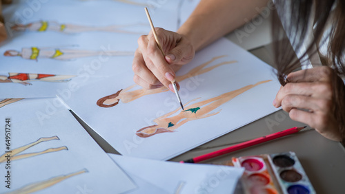 Faceless woman draws sketches of swimwear. Close-up of the hands of a fashion designer.