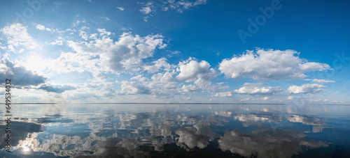 Tablou pe pânză Panorama of the calm mirrored Kama River in Russia, Perm Krai, blue sky with clouds and the sun reflected in the water