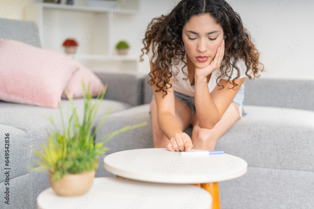 Nervous woman checking a pregnancy test to see the results Nervous woman checking a pregnancy test to see the results