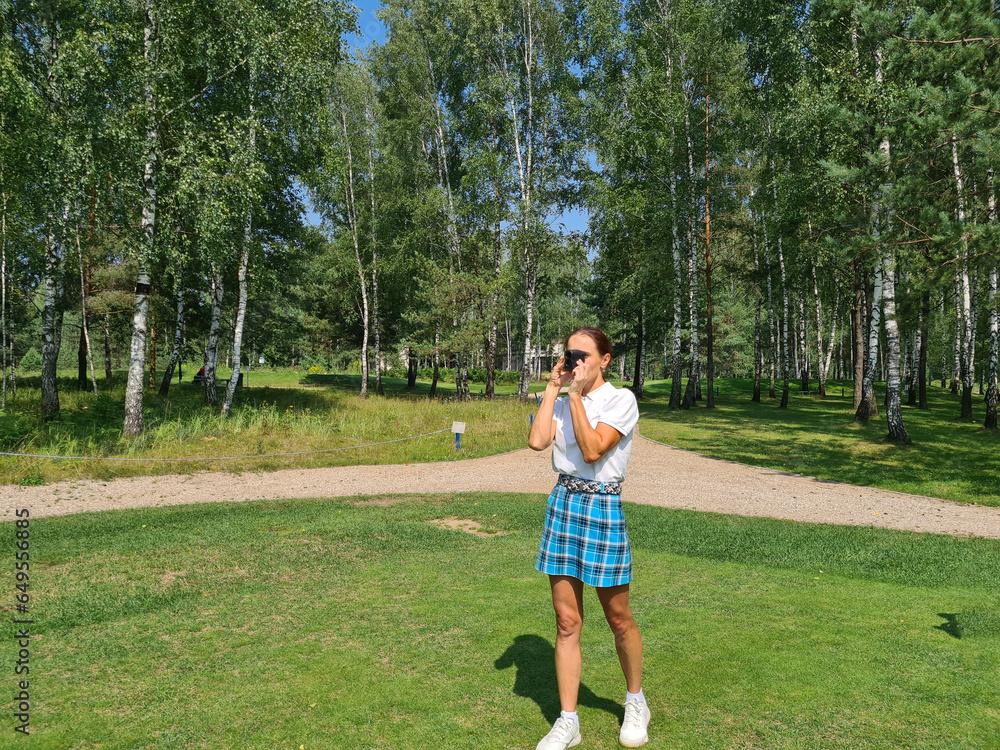 Woman golfer looks into rangefinder to measure distance Woman golfer looks into rangefinder to measure distance