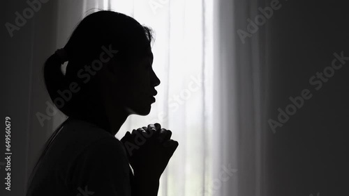Silhouette of a women is praying to God in the morning room. Praying hands with faith in religion and belief in God on blessing background. Power of hope or love and devotion. photo
