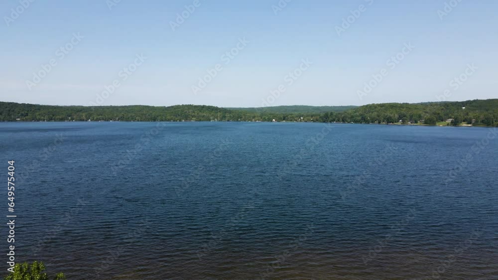 Slow motion push in over trees to empty clear blue lake on sunny day Slow motion push in over trees to empty clear blue lake on sunny day
