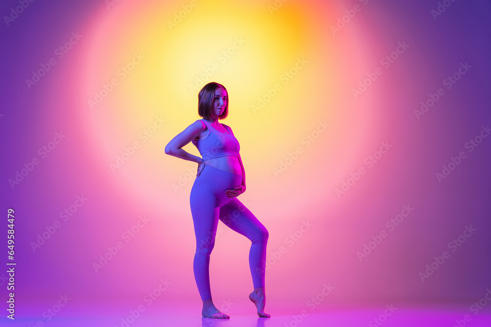 Sporty pregnant womanagainst color background