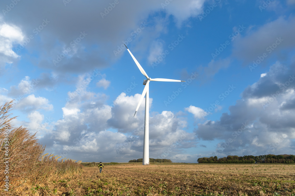 Renewable Energy Stroll: Man Amongst Wind Turbines on Plowed Field Renewable Energy Stroll: Man Amongst Wind Turbines on Plowed Field
