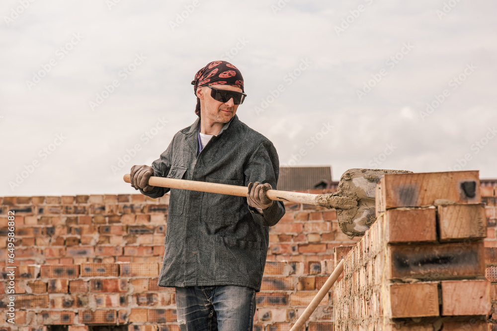 An experienced worker works on the construction of a brick house An experienced worker works on the construction of a brick house