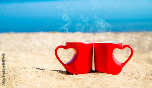 two heart shaped mugs with tea on the seash photo