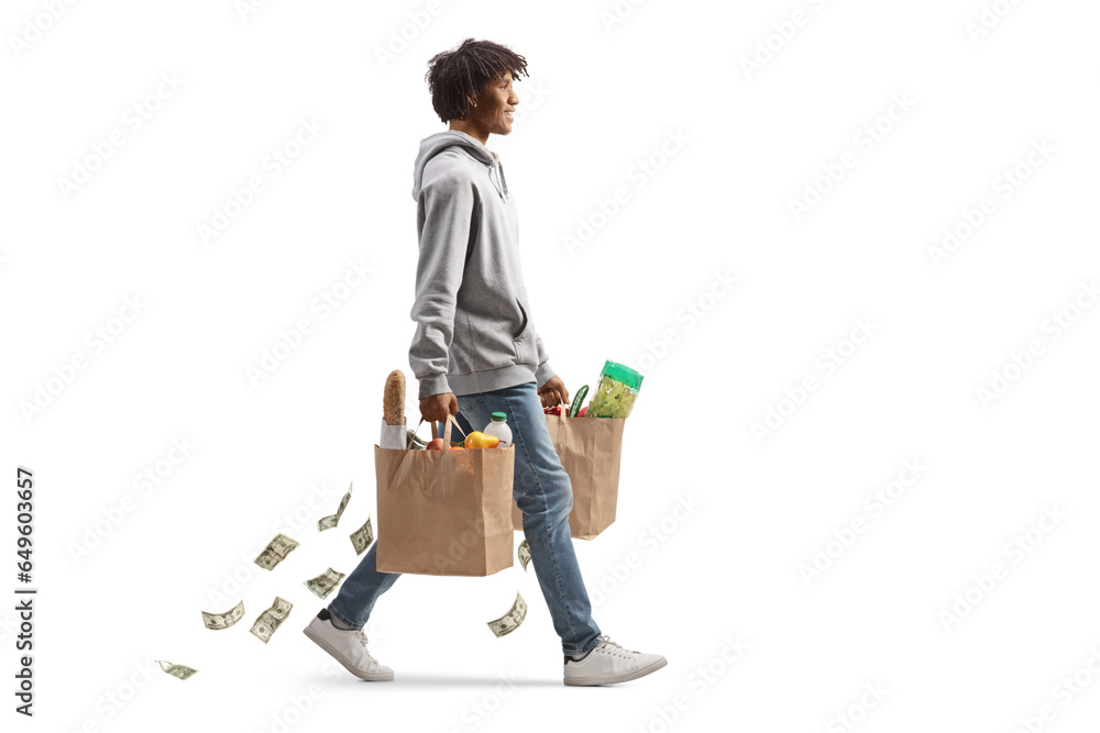 Full length profile shot of a young african american man with grocery bags walking and losing money Full length profile shot of a young african american man with grocery bags walking and losing money