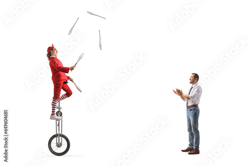 Man giving applause to an acrobat riding a giraffe unicycle and juggling photo