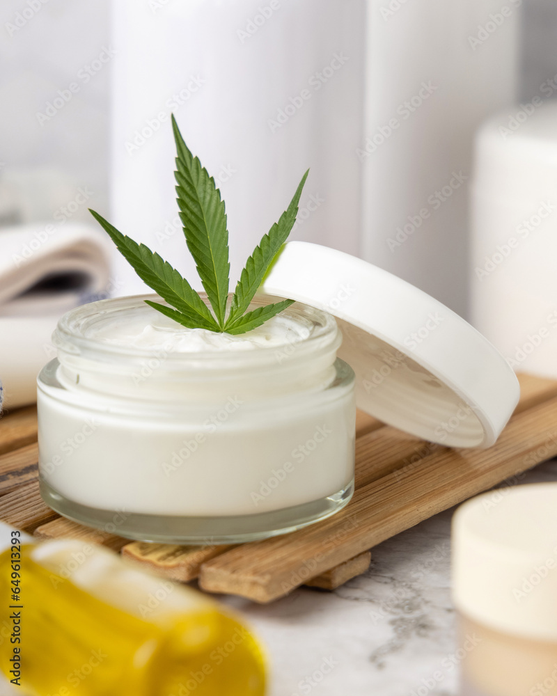 Opened cream jar with green cannabis leaves close up, organic natural CBD cosmetic Opened cream jar with green cannabis leaves close up, organic natural CBD cosmetic
