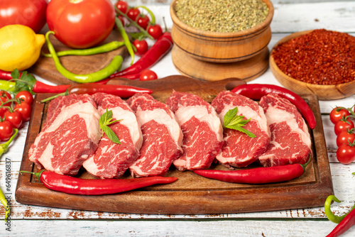 Veal entrecote meat on wood background. Raw beef rib eye steak with herbs and spices