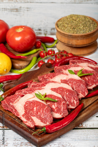 Veal entrecote meat on wood background. Raw beef rib eye steak with herbs and spices
