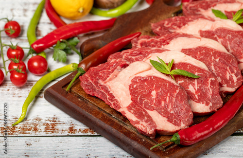 Veal entrecote meat on wood background. Raw beef rib eye steak with herbs and spices. Free space for text. copy space