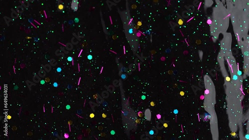 Colorful glitter sparkle confetti background liquid drops of paint color flow down on black canvas. Dark multicolored glitter paint dripping on the black wall. Festive party background