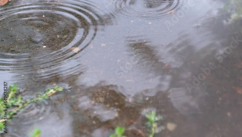 4k vídeo gotas de lluvia cayendo sobre un charco de agua creando ondas. photo