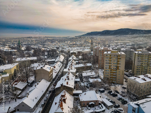 Budynki i bloki mieszkalne miasta Bielsko-Biała w zimie widoczne z lotu ptaka, w tle góry Beskidu i lekko zachmurzone niebo  © Andrzej