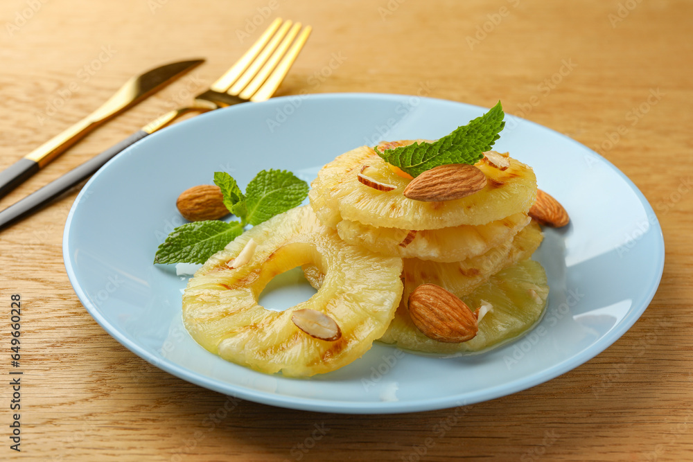 Tasty grilled pineapple slices, almonds and mint on wooden table, closeup Tasty grilled pineapple slices, almonds and mint on wooden table, closeup