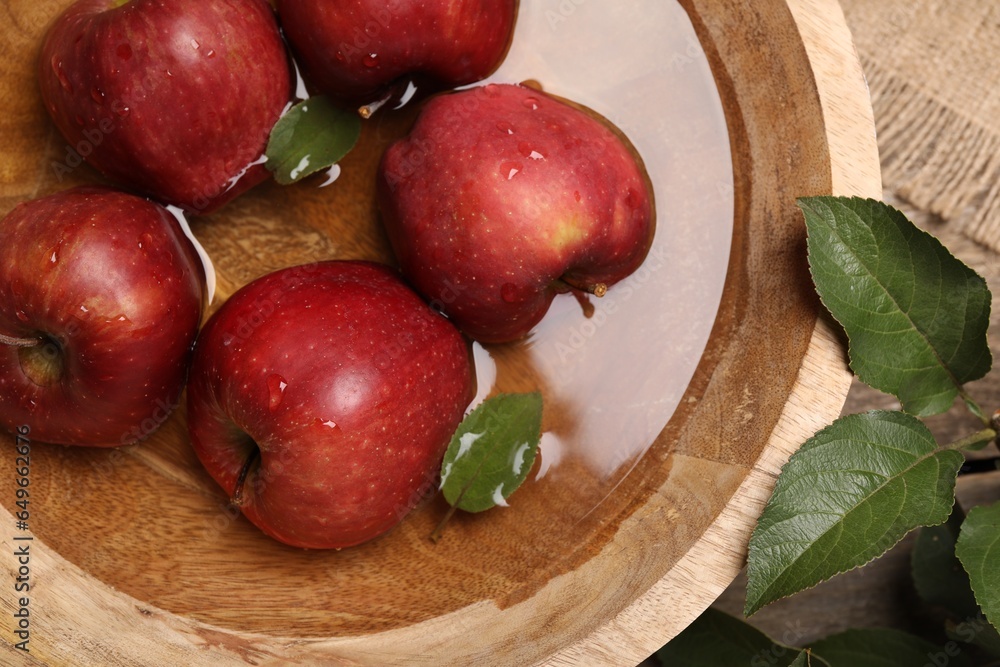 Fresh red apples in bowl with water and leaves on table, flat lay Fresh red apples in bowl with water and leaves on table, flat lay