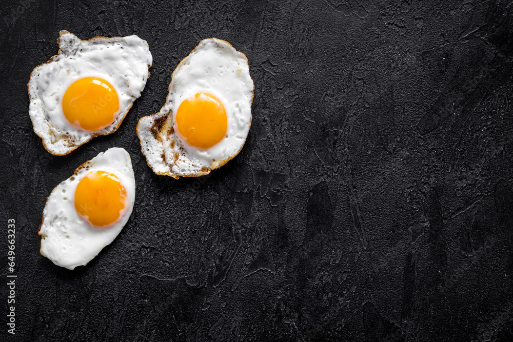 Fried eggs pattern on black background, top view. Breakfast concept Fried eggs pattern on black background, top view. Breakfast concept