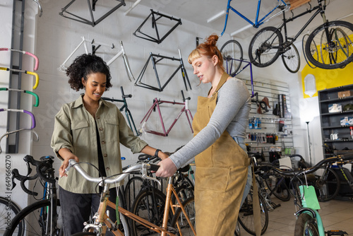 Young adult female shopping for a bicycle in a flea market being given advice by sales assistant