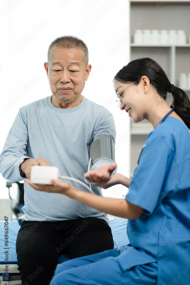 Fototapeta premium Female doctor checking elderly patient blood pressure at clinic and filling patient history in the morning.